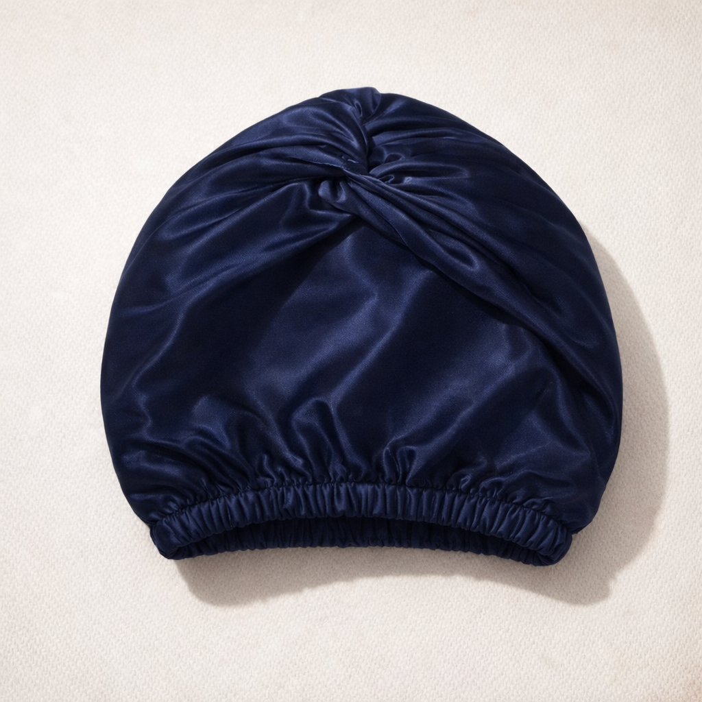 De zijden slaapmuts in marineblauw, gevouwen op een lichte ondergrond