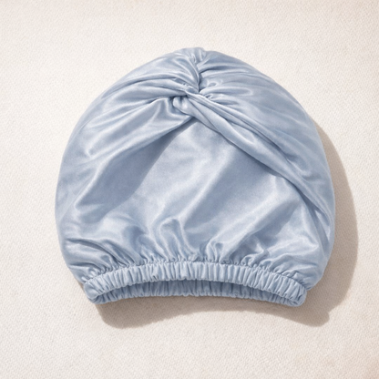 De zijden slaapmuts in poederblauw, gevouwen op een lichte ondergrond